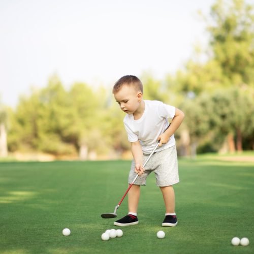 little-boy-playing-golf-with-golf-club-on-green-fi-2023-11-27-05-34-35-utc.jpg